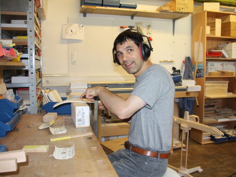 Ein Bewohner sitzt in der Werkstatt und schleift eine Kelle