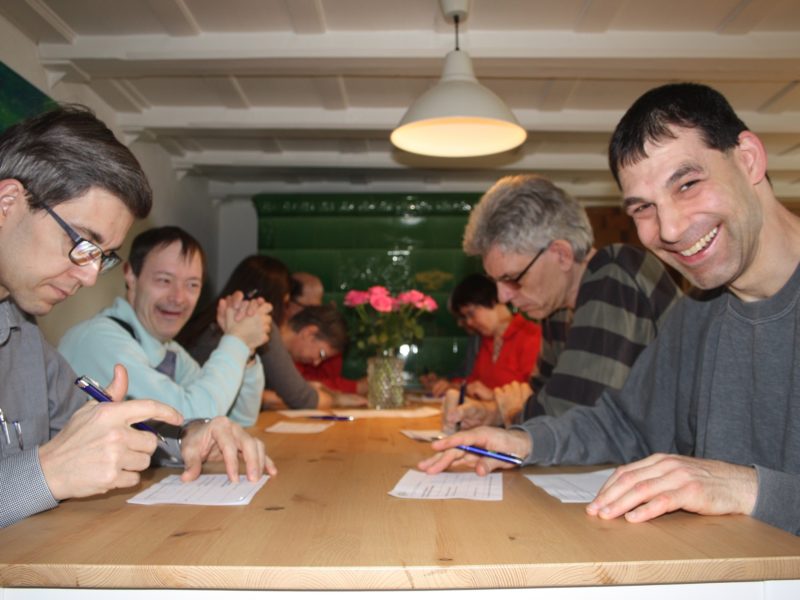 Die Bewohner sitzen am Tisch und füllen eine Umfrage zu Bewegung aus