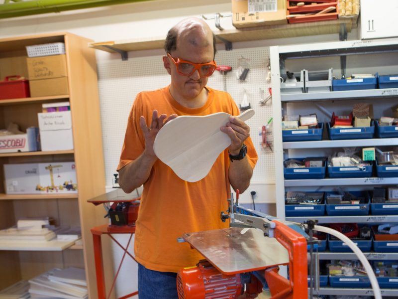 Ein Bewohner begutachtet ein Brett aus Holz, das er gerade ausgesägt hat